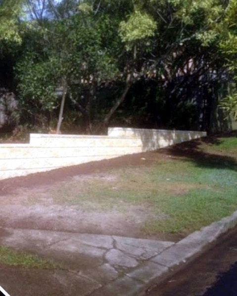 A sandstone block retaining wall along a cleared yard
