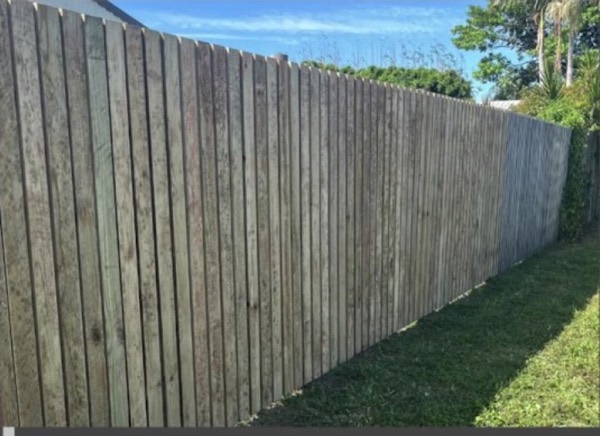 A timber paling fence running along a green lawn