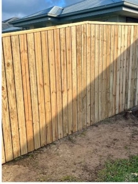 A corner of a new timber paling fence on bare ground