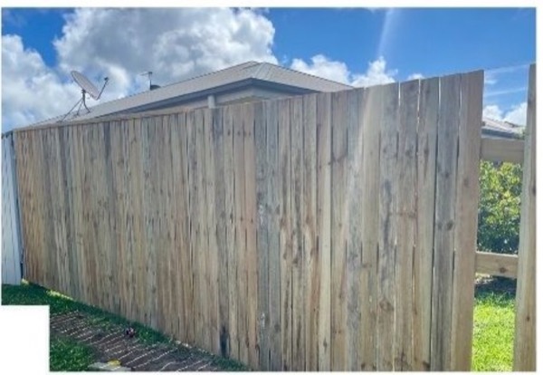 A tall timber paling fence beside a house roofline