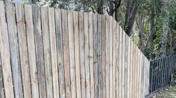 A timber paling fence line beside a neighbouring metal fence