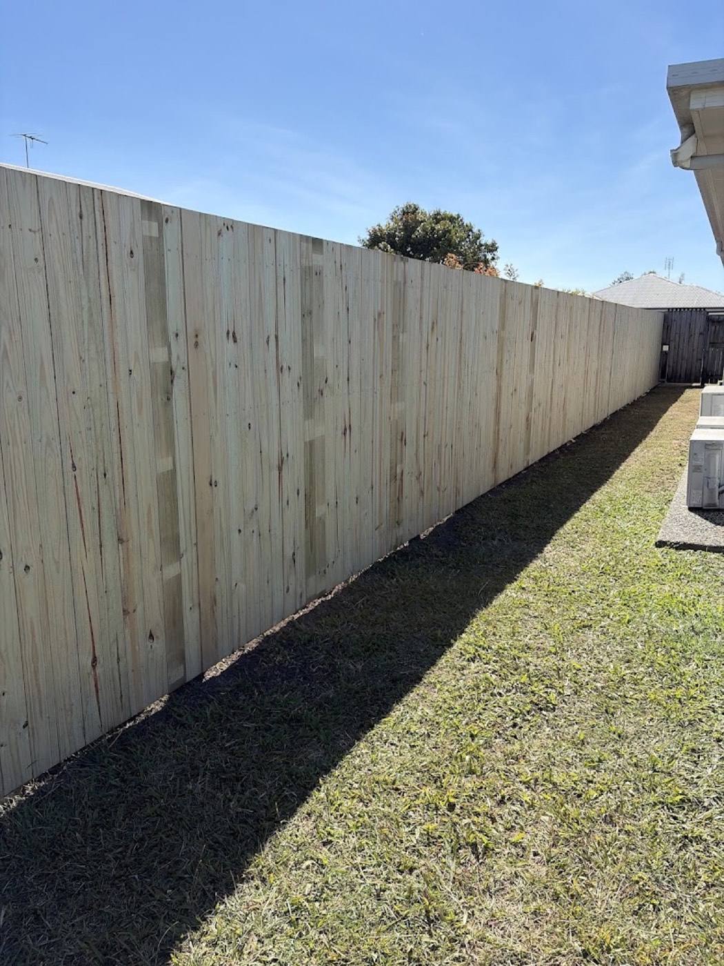 A newly built timber paling fence running the length of a Mackay backyard