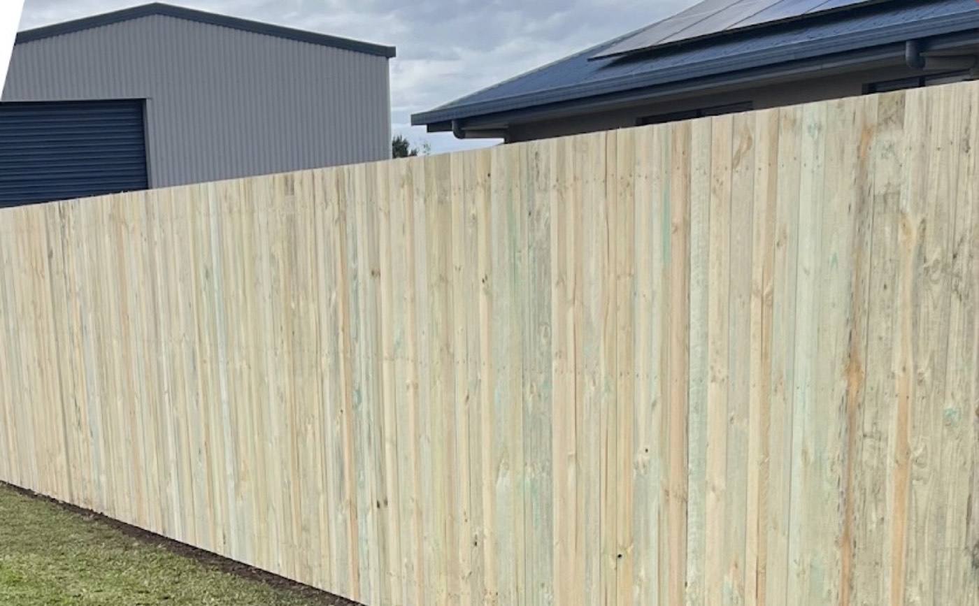 A new timber paling fence beside a mown lawn and a shed