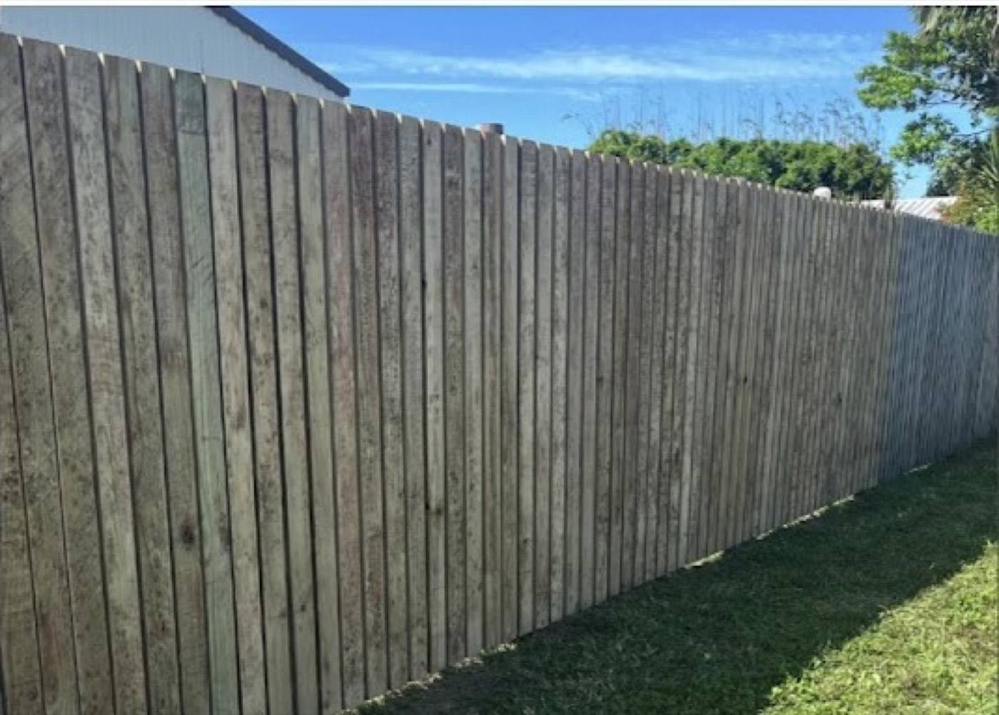 A timber paling fence line under a clear blue sky