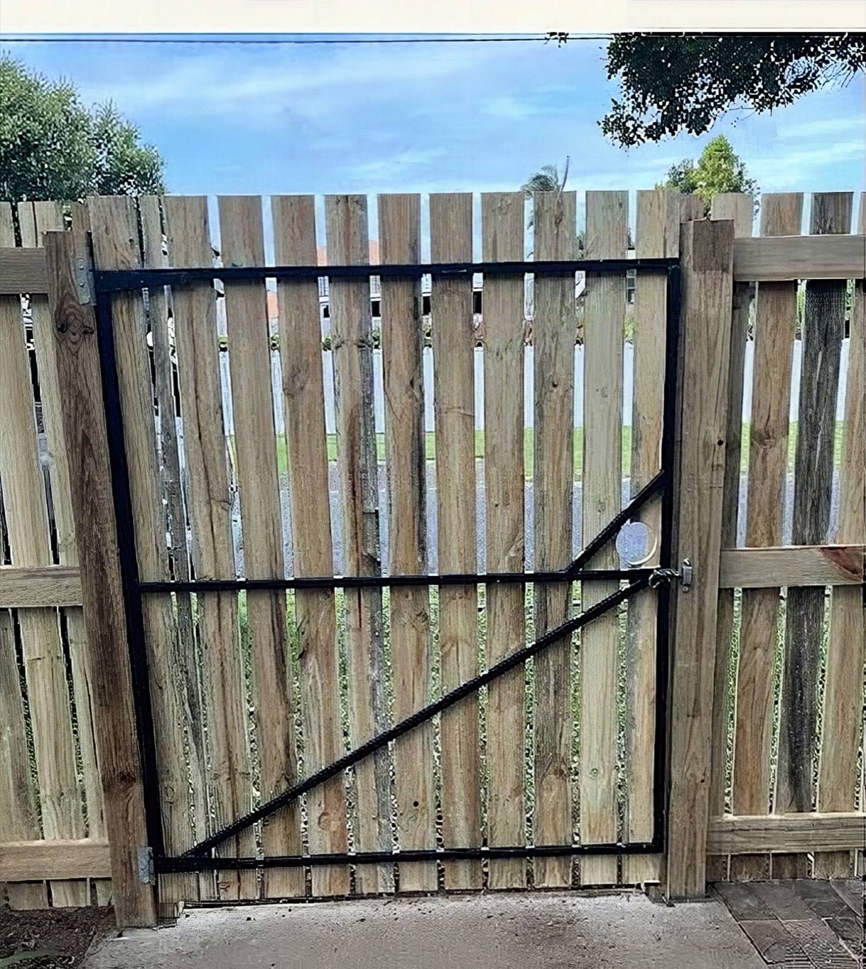 A timber gate on a steel frame set into a paling fence